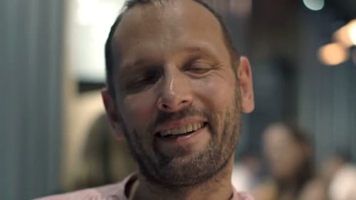 Portrait of Happy, Young Man Sitting in Cafe at Night 30s