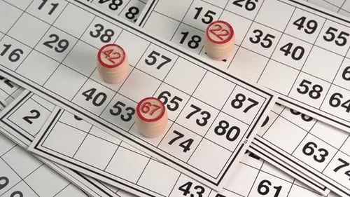 Lotto cards with numbers board game with wooden barrels rotating background top view. Bingo games