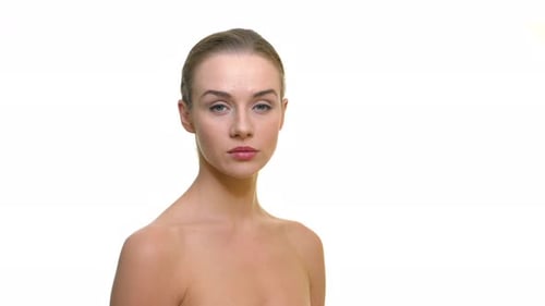 Young beautiful naked model in the studio looking seriousely to camera, on a white background. For c