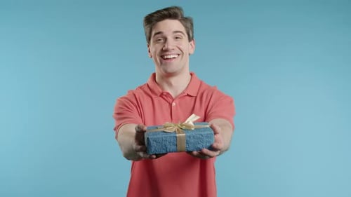 Smiling Young Man Holds Out Gift