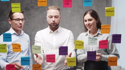 Team of Business People is Doing Brainstorm at a Meeting Using Stickers on the Glass Office Workers