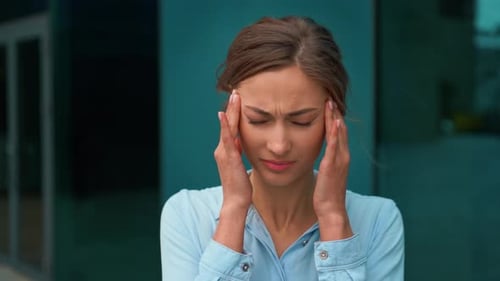 Overworked Businesswoman Suffering From Headache Outside Office