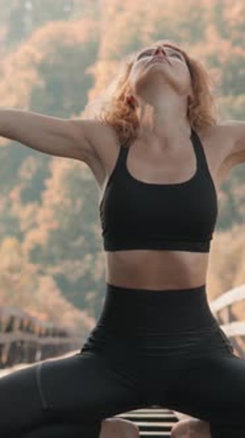 A Serene Woman Practices Yoga on an Old Bridge Surrounded By Vibrant Autumn Leaves Creating a