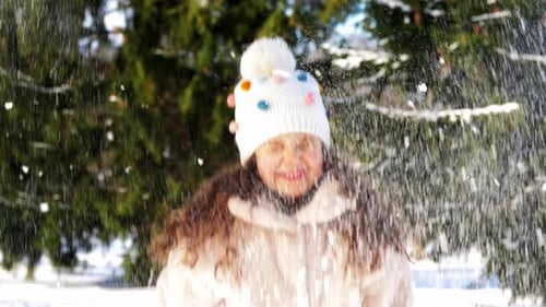 Konzept für Kindheit, Freizeit und Jahreszeit — Fröhliches kleines Mädchen wirft Schnee im Winterpark