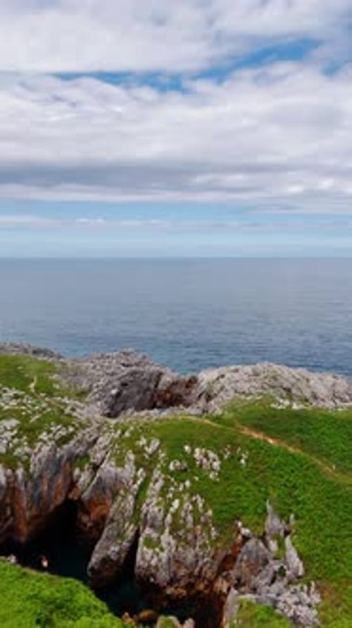Spectacular mountains covered with green grass. A person on a boat rows by the water at the rocks