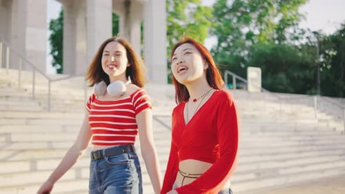 Two Beautiful Young Women Walk Down the Street or Park Holding Hands A Couple of Girls Walk Hand in