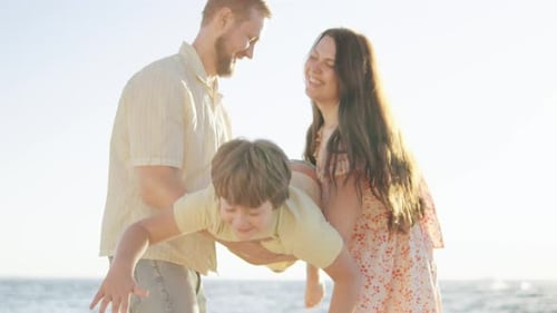 Family Enjoying a Sunny Day at the Beach Playing with Their Son Hold Cute Little Kid Son Pretend