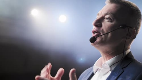 Man Giving Speech with Microphone in Bright Room