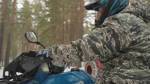Rider in Camouflage Controlling Snowy Terrain Vehicle Frozen Forest Scene Featuring Rider in
