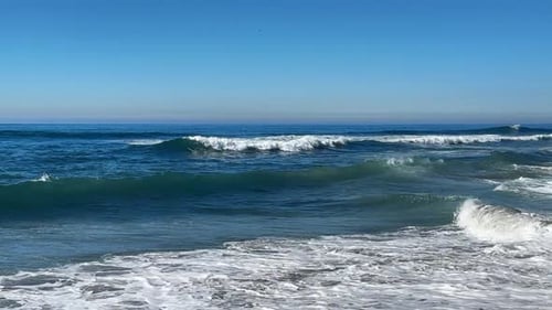Las olas del océano chocan y se rocían juntas durante King Tide sobre el océano azul y el cielo azul.