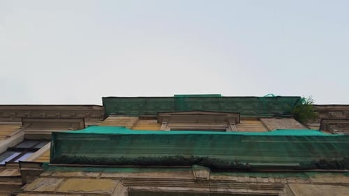 A Detailed View Showcasing a Buildings Beautiful Facade Adorned with a Green Canopy Under a Clear