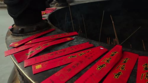 Close-Up of Red Offering Envelopes and Lit Incense Sticks at Chinese Temple