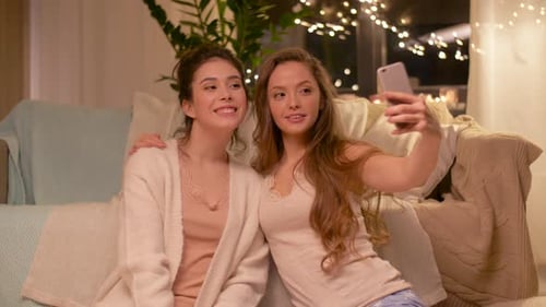 Smiling women pose for selfie indoors at night