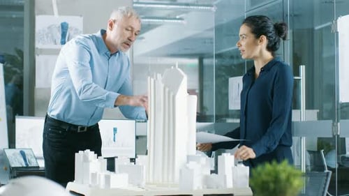 Two Professional Male and Female Architectural Engineers Work with Blueprints and on a Building Mod