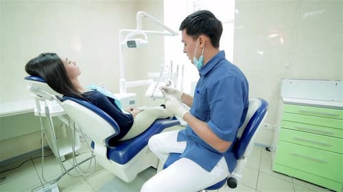 Dentist Examining Female Patient in Examination Room