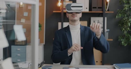 Businessman Wearing Virtual Reality Glasses Gesturing Moving Hands Sitting at Desk in Office