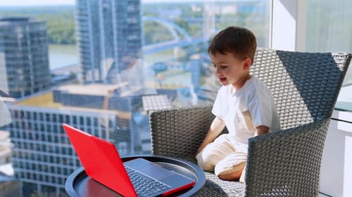 Little Boy Using Laptop Computer on Balcony