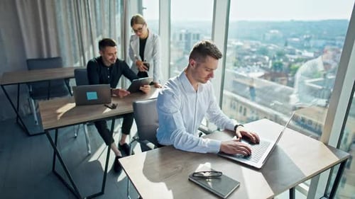 Junges Büroteam, das im Büro arbeitet. Mann im weißen Hemd sitzt an der Rezeption und arbeitet am Laptop.