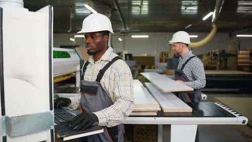 Two Factory Workers Operate a CNC Machine to Cut Laminated Wood Panels
