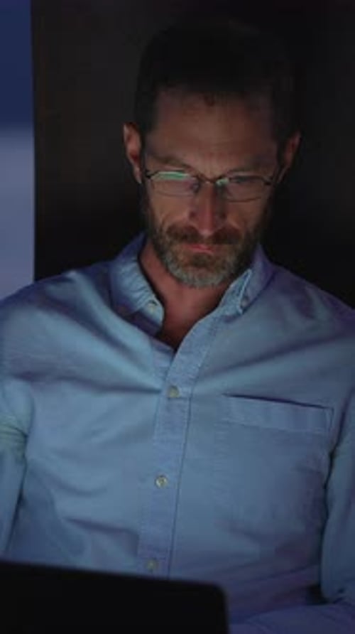Focused and Professional Individual Working Late at Night on Their Laptop in an Office Setting