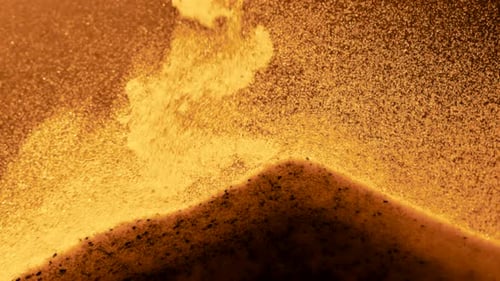 Little grains of sand particles falling on the sand pile in slow motion