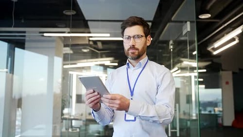 Portrait of a smiling admin IT engineer works on a digital tablet standing in business office