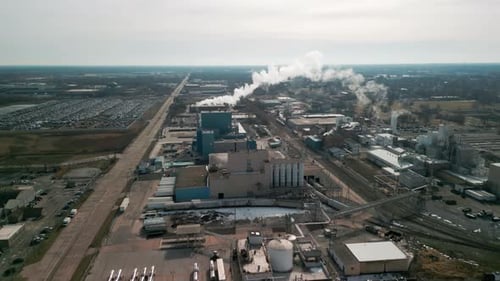 Wide Drone Shot of Big Factory and Smoke Comes Out Chimney of Factory Plant Polluting Environment