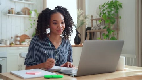 Woman Video Calling and Taking Notes at Home