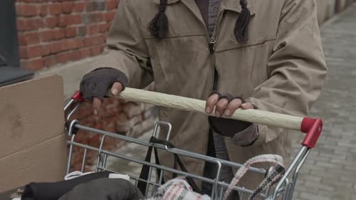 Midsection of Vagabond Pushing Shopping Cart with Belongings Walking down Street