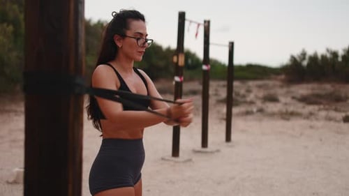 Athletic Woman Exercises with Resistance Band Outdoors