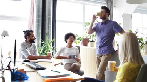 Happy multiethnic business team drinking coffee and talking at break in the office