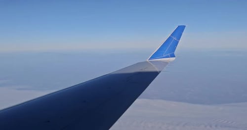 Wunderschöner Blick vom Flugzeugfenster auf einen Flugzeugflügel mit Erde und Himmel, bewölktem Himmel
