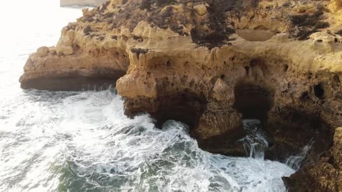 Aerial 4K drone footage revealing the rocky coastline cliffs near city of Carvoeiro, Portugal.