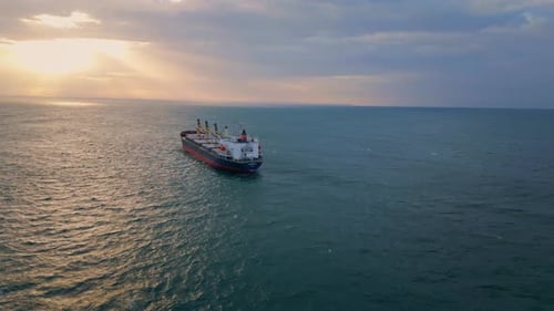 Cargo Ship Sailing On Wavy Ocean At Sunset