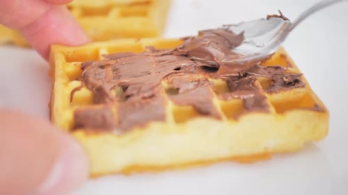 Ich verteile Schokolade auf einer Wiener Waffel mit einem Löffel, während die Kamera durch sie hindurchgeht