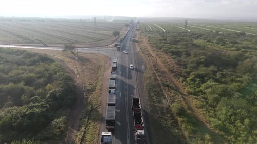 Cinematic drone descent onto a large number of cargo trucks stuck in a long queue on a highway befor