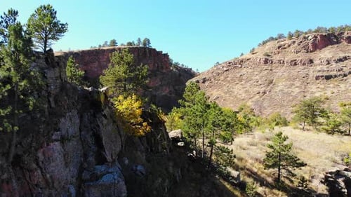 Rocky Hillsides And Ridges With Green Yellow Autumn Trees At The Base. 4K Drone.