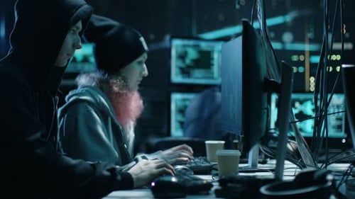 Young Hackers Working at Computers in Dark Room