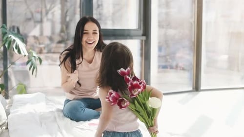 Young Girl Giving Flowers to Her Happy Mother