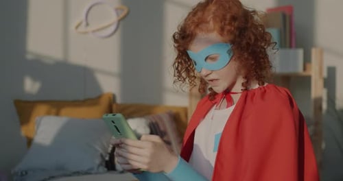 Girl Dressed As Superhero Uses Smartphone Indoors