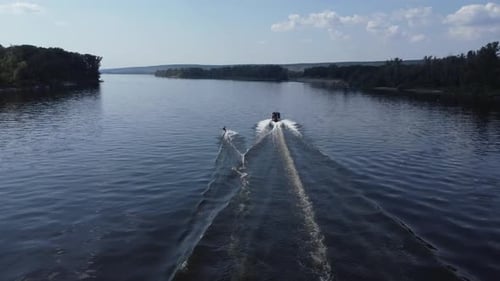 A Young Man Rides a Wakeboard A Sports Guy Rides on the Water on a Board Behind a Boat Top View From