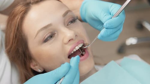 Woman Receives Dental Exam by Dentist with Tools