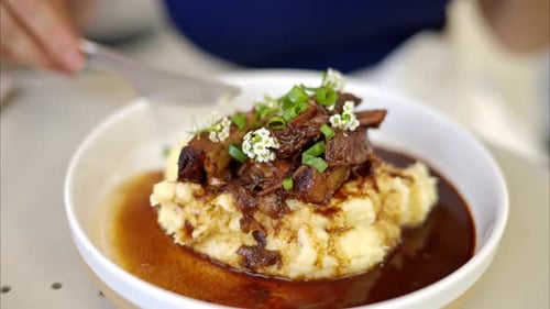 Woman eating pork ribs with smashed potatoes at a restaurant