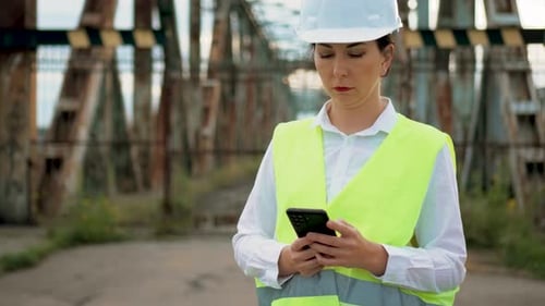 Woman Engineer Builder in Protective Vest and Helmet Inspect Metal Bridge Construction Using