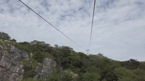 Passing red cable car sightseeing transportation heading up scenic mountain valley hillside