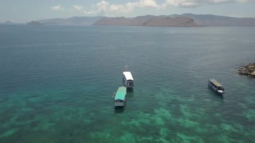 Small cruising boats on the Idyllic waters off the coast of Pink Beach in Komodo Island, Indonesia -