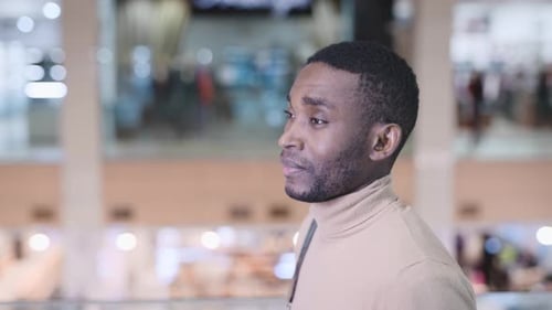 A Young African Man is Walking Through the Mall