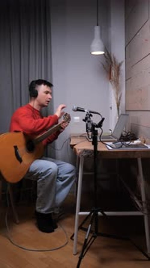 Young Man Plays Guitar and Sings into Microphone