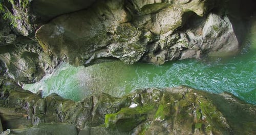 River flows in narrow rocky gorge. Mountain stream with emerald green water.