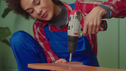 Woman Drives Screw into Wood with Power Drill
